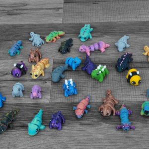This is a photo of a 3D printed articulating mini animal fidget toy made from eco-friendly PLA plastic, designed for stress relief and as a cute desk toy. Displayed as part of a collection of colorful, whimsical articulated animal figurines by a small USA-based business