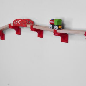 A children's playroom with wooden train tracks mounted on the wall using eco-friendly PLA plastic wall mounts. The tracks, compatible with Brio, Thomas & Friends, Lillabo, and Ikea sets, are arranged creatively, freeing up floor space and showcasing a fun, interactive play area. The scene highlights the sustainable and locally made nature of the mounts, emphasizing their practicality and support for imaginative play